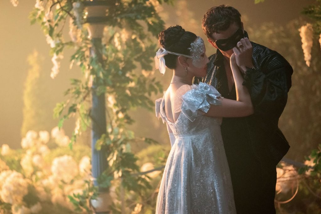 A masked Benedict Bridgerton kisses the hand of a mystery woman.