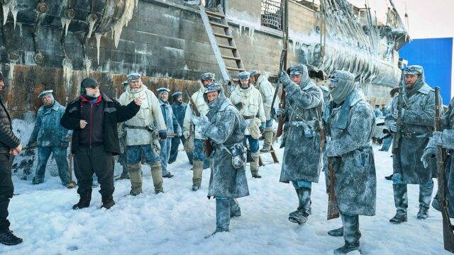 FRANKENSTEIN. (L to R) Writer/Director Guillermo del Toro Lars Mikkelsen as Captain Anderson, Nikolaj Lie Kaas as Chief Officer with cast members on the set of Frankenstein. Cr. Ken Woroner/Netflix © 2025.