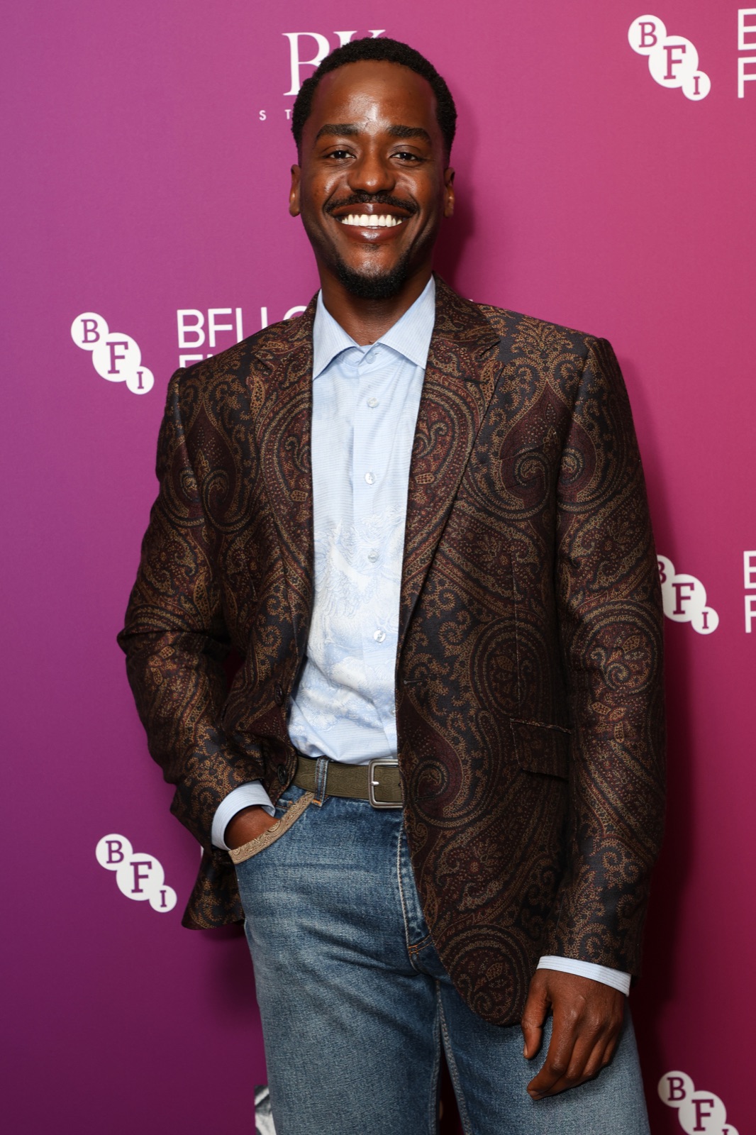 Ncuti Gatwa smiling in a patterned brown jacket at the BFI London Film Festival.